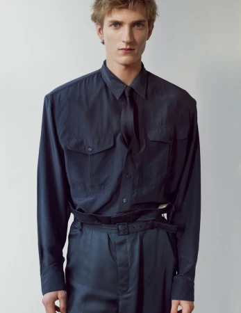 A male model wearing a dark navy buttoned shirt and matching trousers against a plain neutral background.
