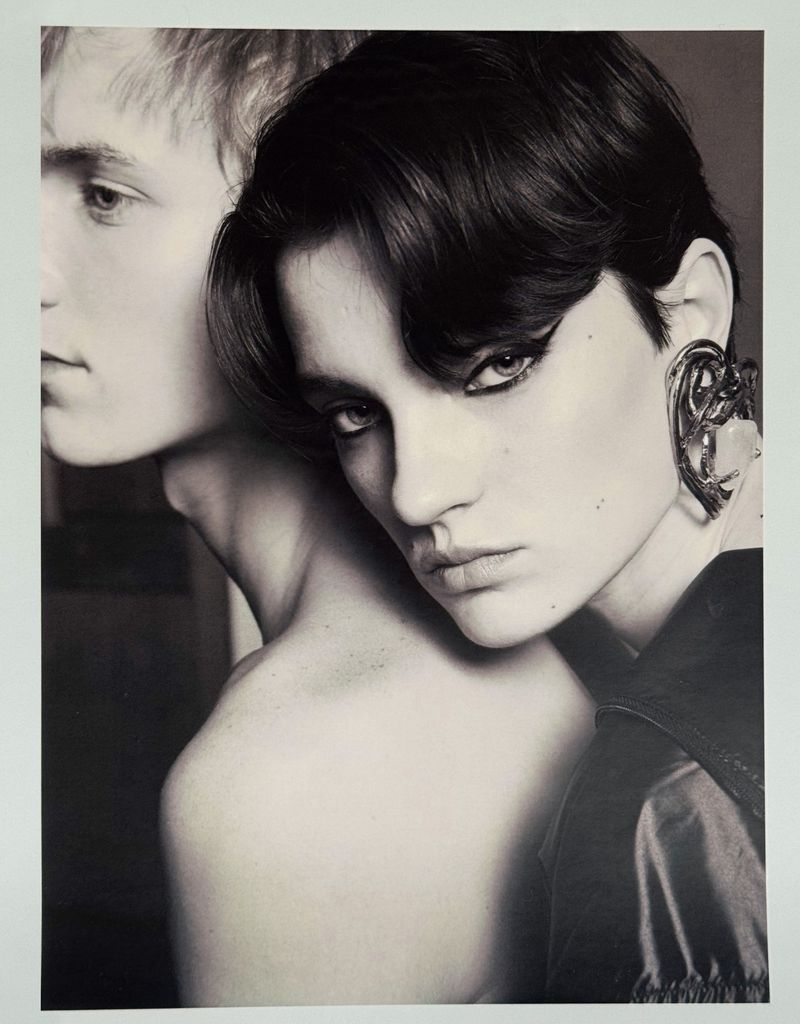 Close-up portrait of a dark-haired woman leaning against a fair-haired man, wearing a prominent ear cuff.