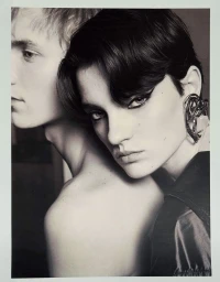 Close-up portrait of a dark-haired woman leaning against a fair-haired man, wearing a prominent ear cuff.