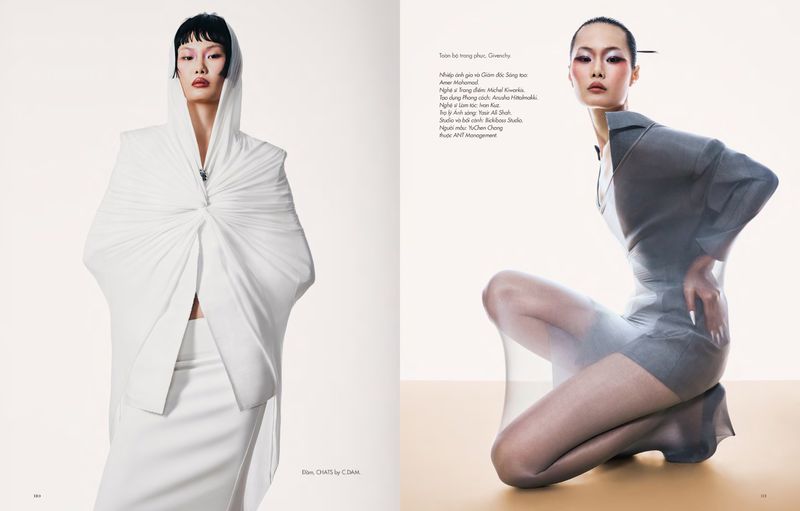 Editorial double-page spread featuring two Asian models in avant-garde white and sheer grey designer fashion against a minimalist studio background
