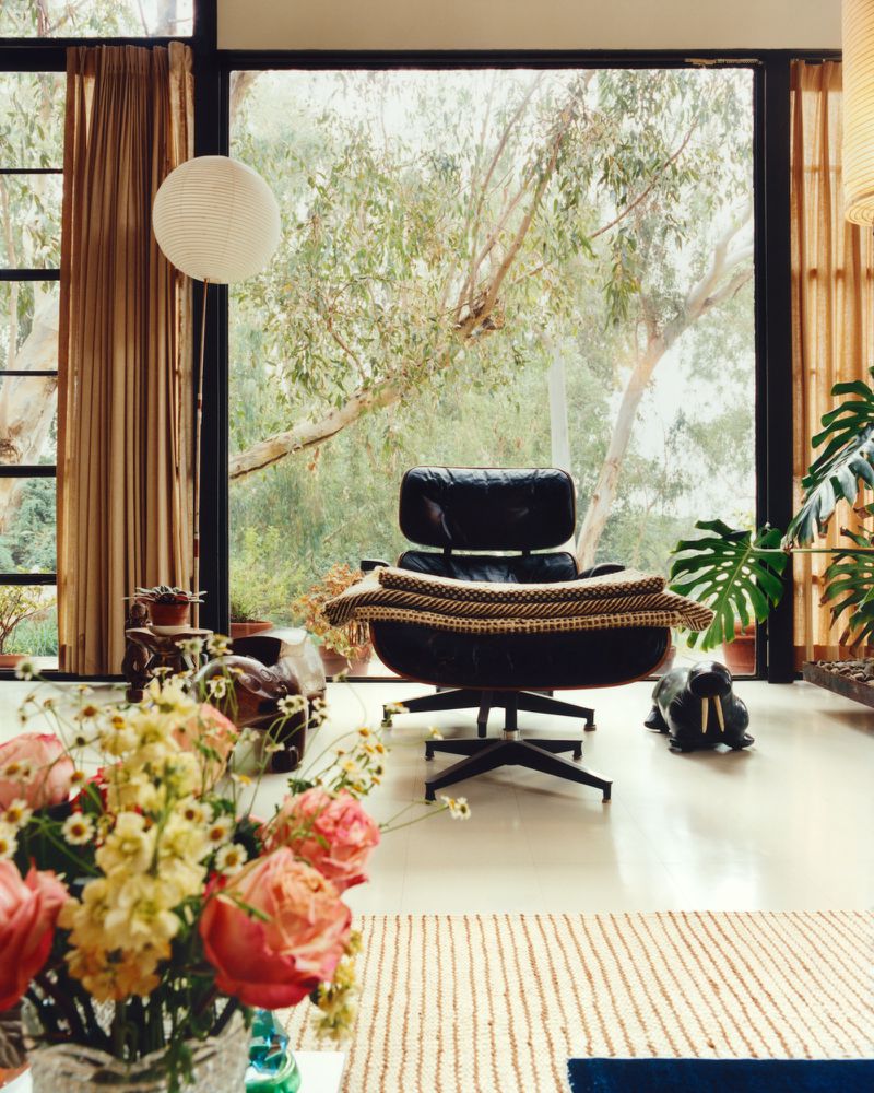Black leather lounge chair positioned in a bright modern interior with large windows overlooking trees