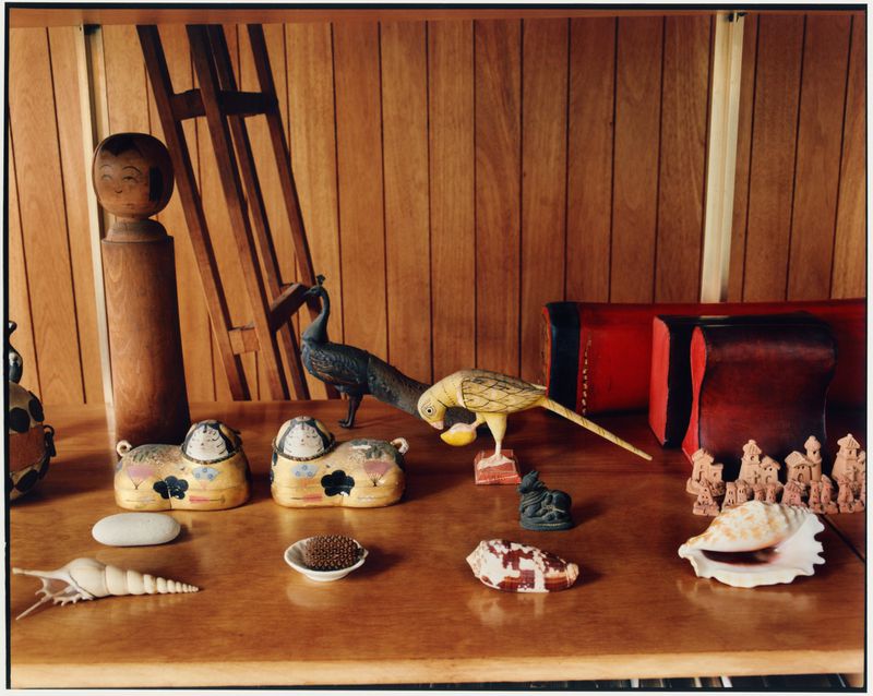 Collection of wooden animal figurines, shells, and decorative objects displayed on a wooden shelf inside the Eames House.