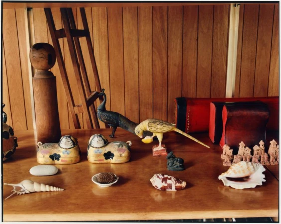 Collection of wooden animal figurines, shells, and decorative objects displayed on a wooden shelf inside the Eames House.
