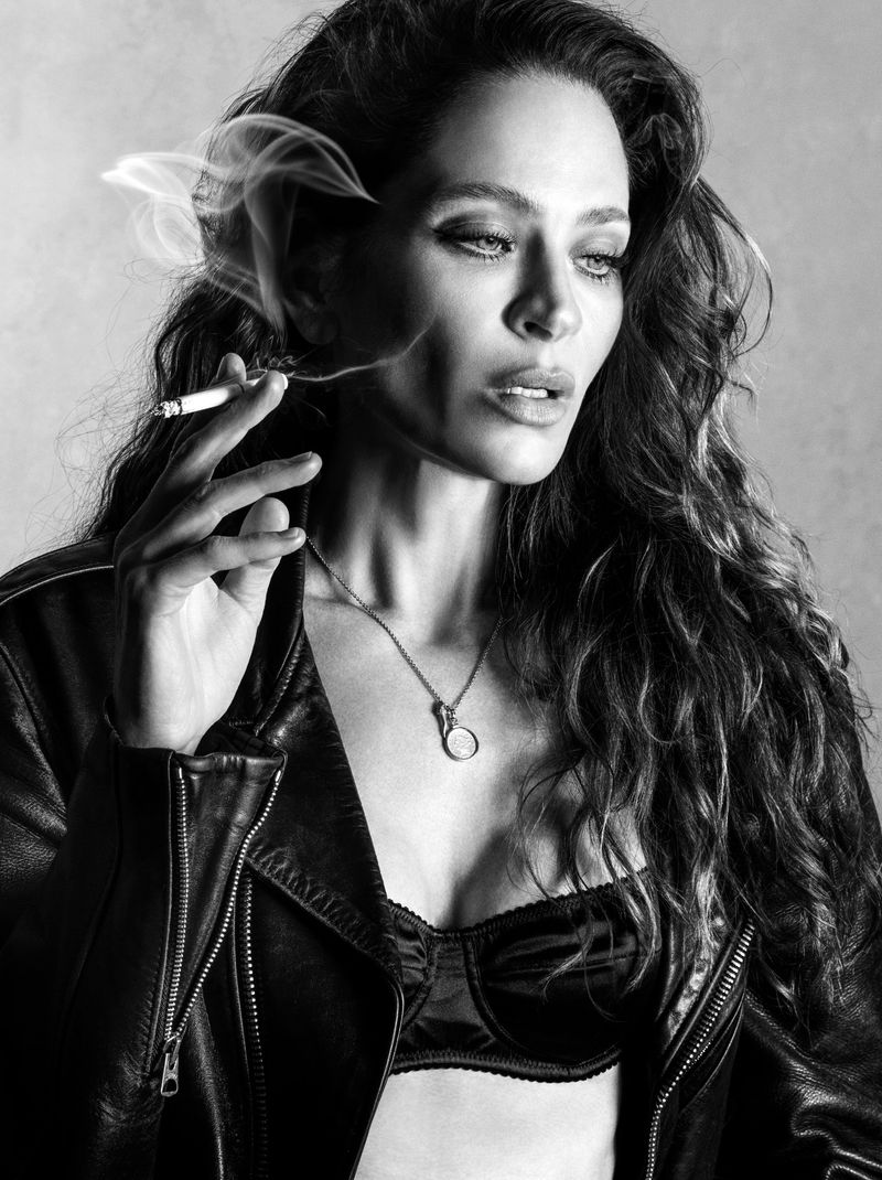 Model Frankie Rayder in a black leather jacket holding a lit cigarette against a plain background in a black and white portrait.