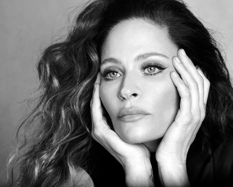 Close-up portrait of model Frankie Rayder with hands framing her face against a neutral background.