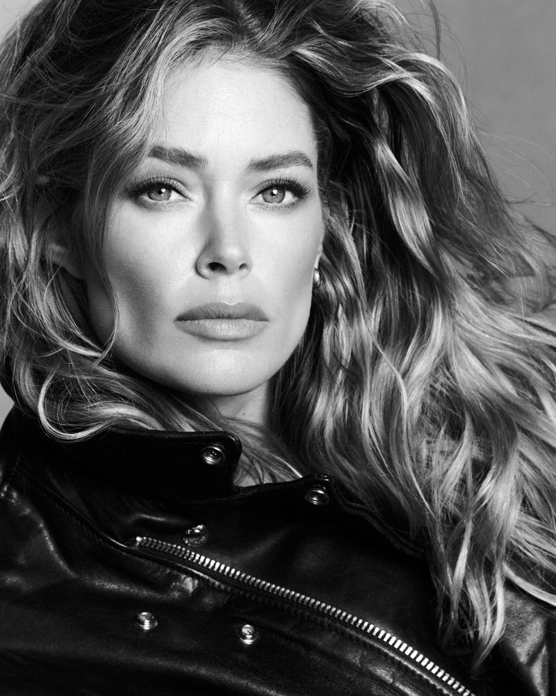 Close-up black and white portrait of model Doutzen Kroes wearing a dark leather jacket with metal snaps.