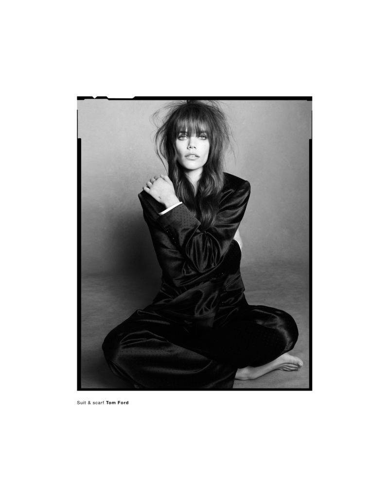 Model Betsy Gaghan seated cross-legged wearing a dark satin suit against a neutral background for Betsy editorial