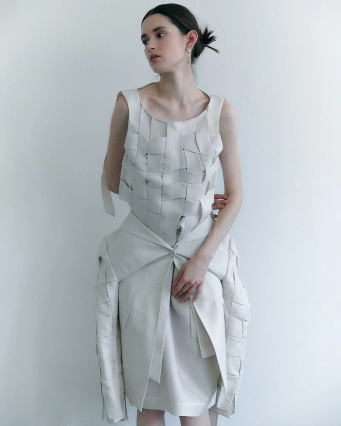 Model in woven cream dress against a bright white background for D'Scene Magazine style story