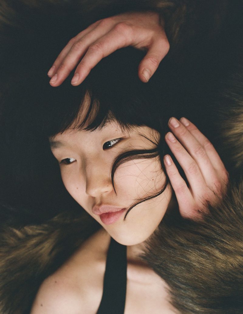 Close-up portrait of model Jiashan Liu with hands framing her face amidst textured fur for The Other Half project