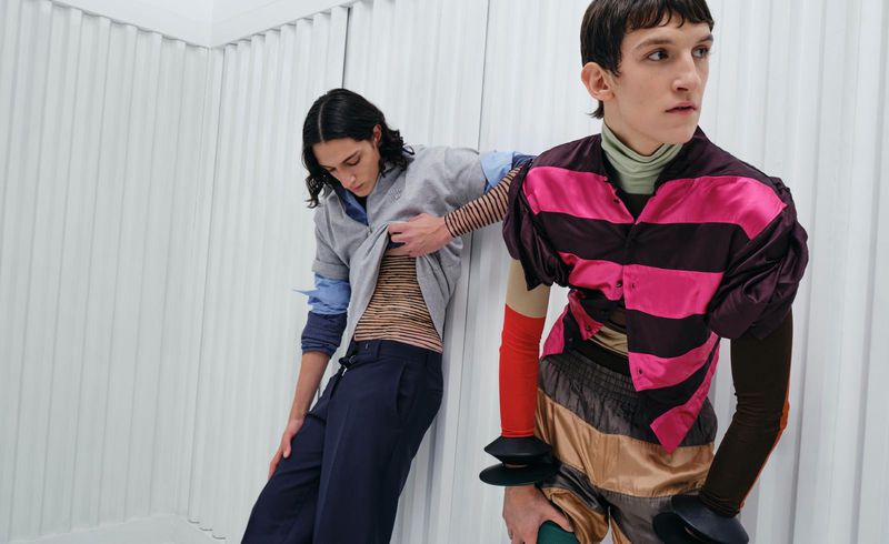Two male models posing against a white vertical paneled wall for an ODDA Magazine fashion editorial.