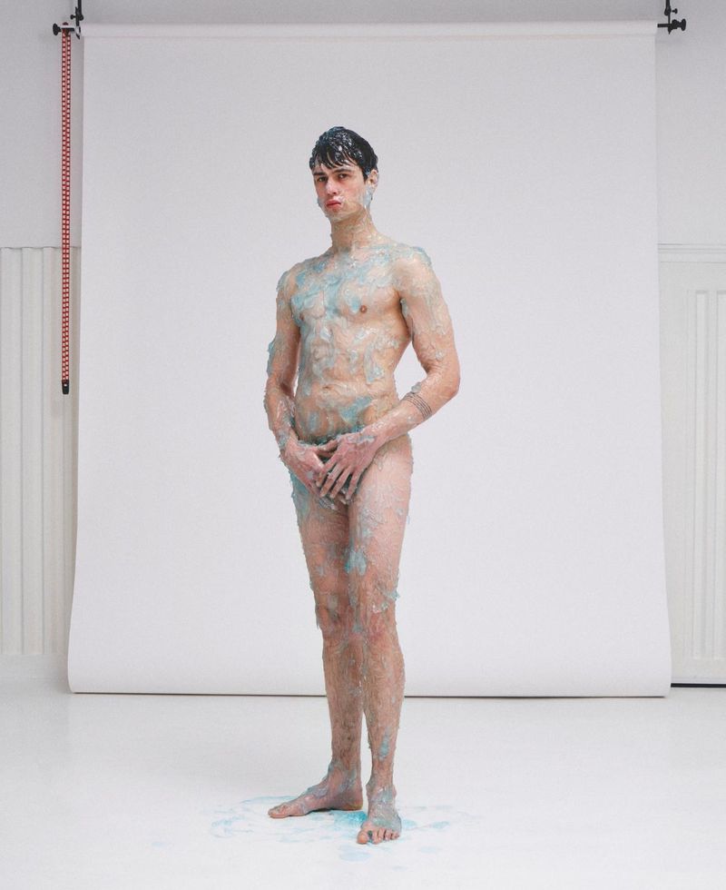 Full-length portrait of a male model covered in gel against a white seamless background for ODDA Magazine