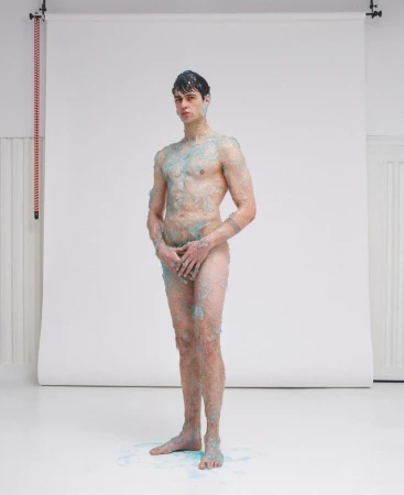 Full-length portrait of a male model covered in gel against a white seamless background for ODDA Magazine