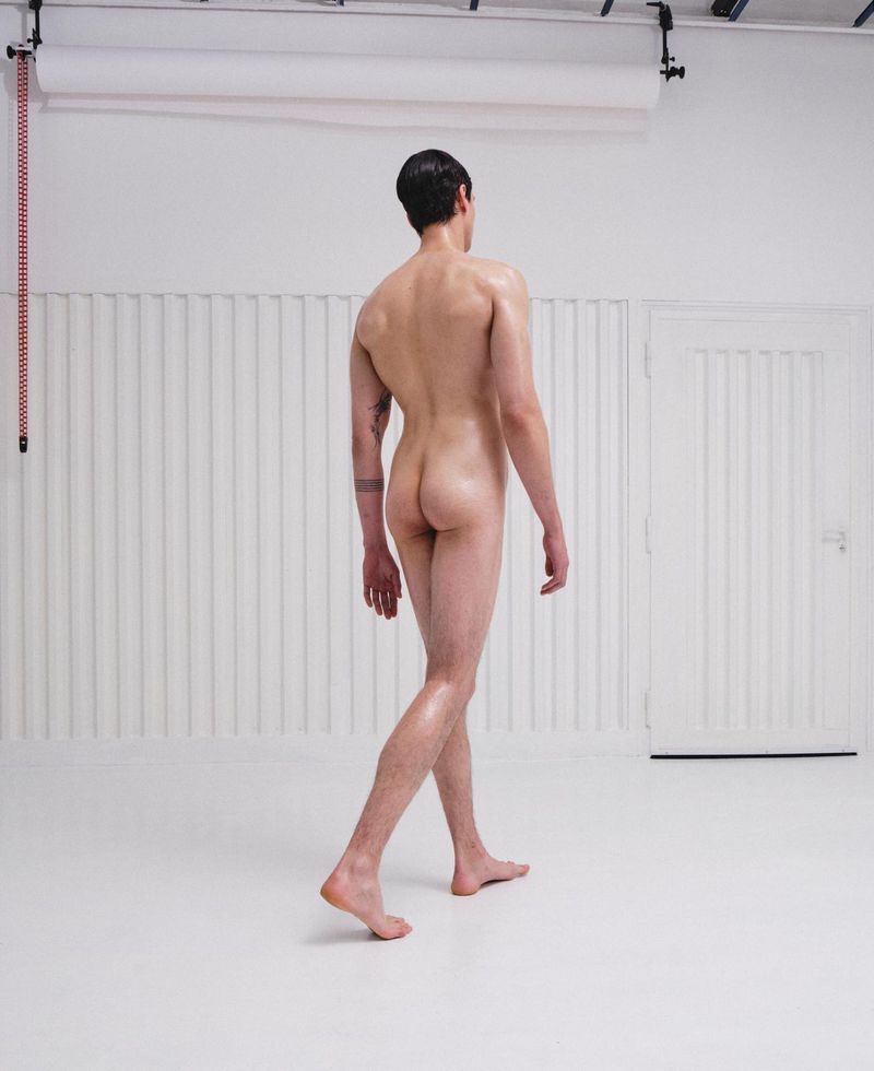 Rear view of a man walking away in a studio setting against a white background