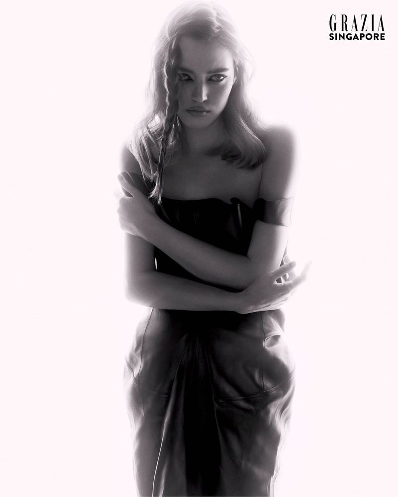 Model Polly Domashych posing in a dark dress against a bright white background for Grazia Singapore
