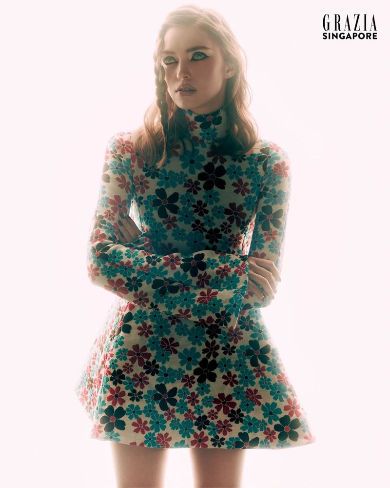 Model Polly Domashych wearing a floral long-sleeve minidress against a bright white background for Grazia Singapore