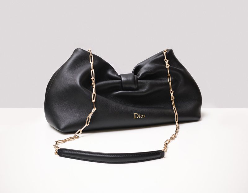 Black leather Dior handbag with gold chain strap displayed on a clean white studio surface.
