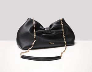 Black leather Dior handbag with gold chain strap displayed on a clean white studio surface.