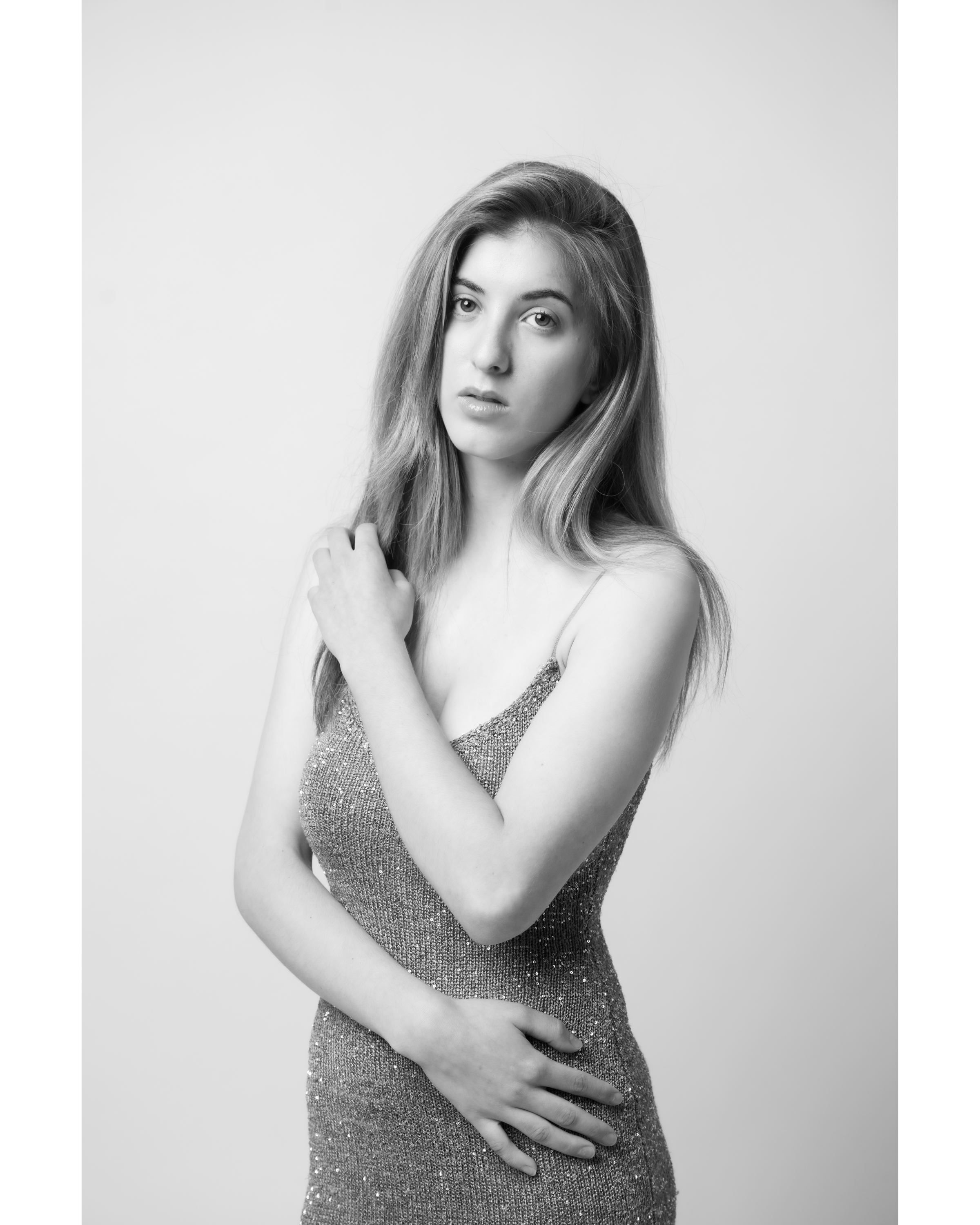 Portrait of a woman in a sparkly dress against a white background. Her hair is blonde and she is in a studio setting.