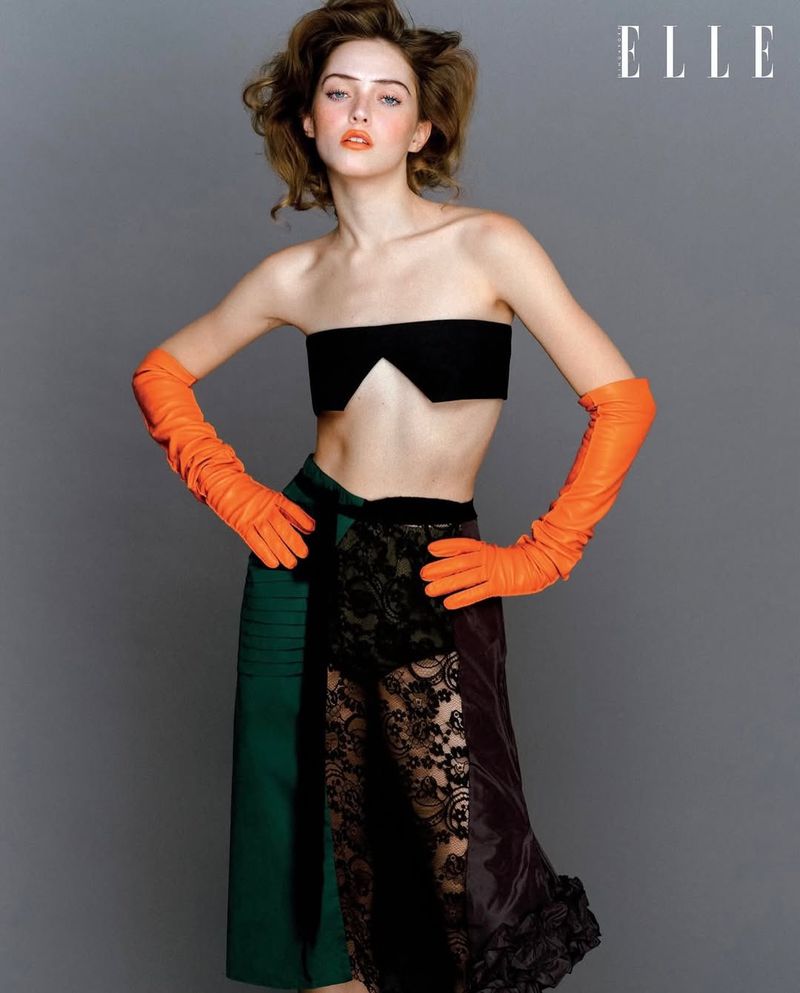 Model in black bandeau top, green skirt, and orange gloves against grey backdrop for Elle Singapore editorial