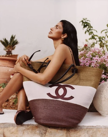 Model Pooja Mor posing outdoors with a large straw tote bag for Grazia UK Shore Things fashion editorial