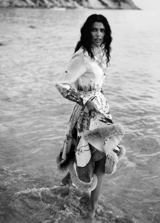 Model Pooja Mor wading in the shallows wearing a patterned dress for Grazia UK Shore Things editorial