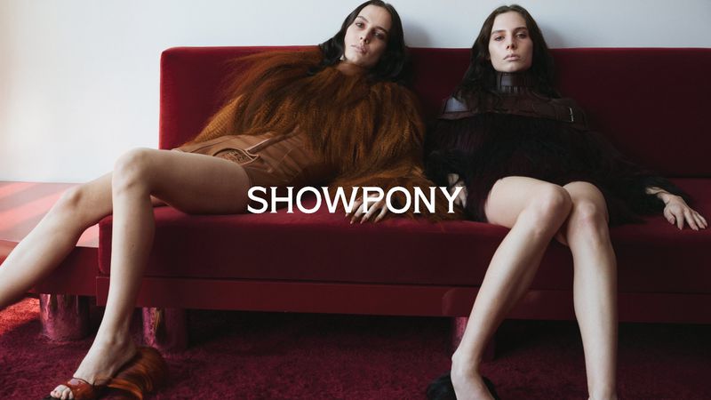 Two female models lounging on a plush red velvet sofa in textured garments with the word SHOWPONY displayed prominently.