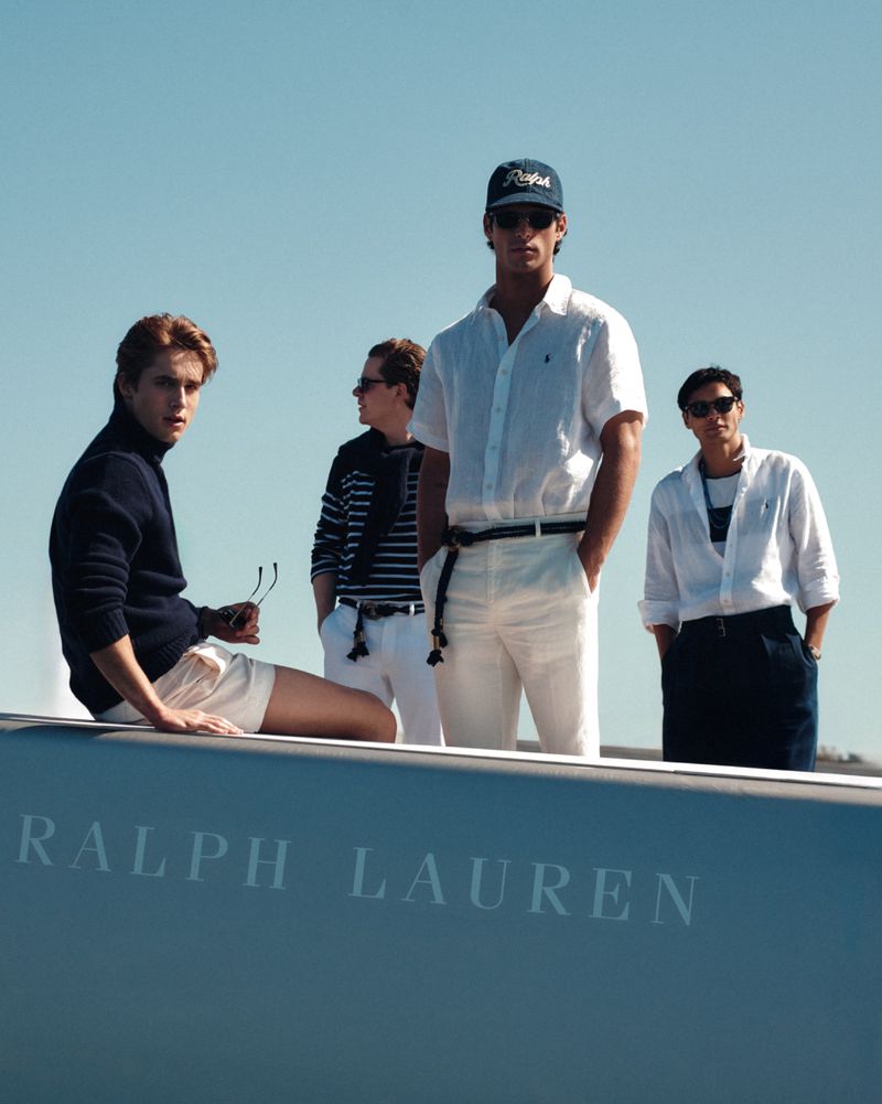 Four men in casual wear on a boat against a clear blue sky, photographed by Hayden Worsfold for Ralph Lauren Fragrances.