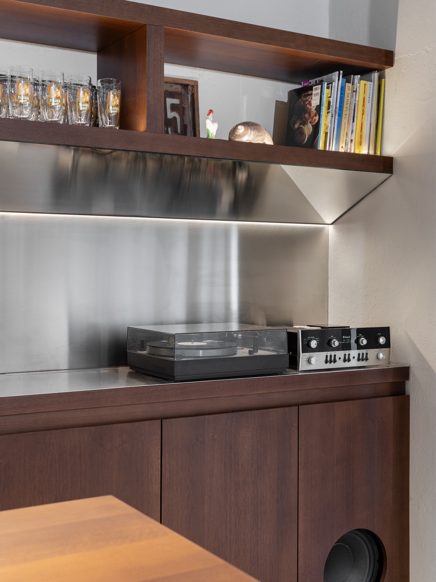 Modern wooden credenza featuring a metallic backsplash with a turntable, audio amplifier, upper display shelf with glassware and books.