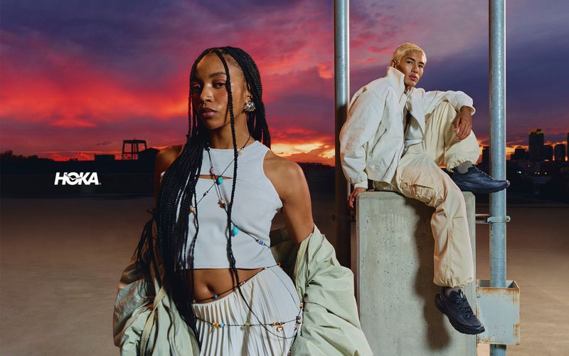 Two models posing outdoors at sunset for the Hoka Mach Remastered campaign, featuring athletic footwear and streetwear apparel.