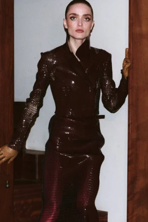Model Gertrud Rose posing in a dark textured jacket and matching skirt framed by wooden doorways for Re-Edition Magazine.