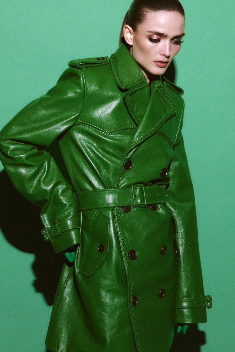 Model Gertrud Rose in a glossy green leather trench coat against a solid green background for Re-Edition Magazine