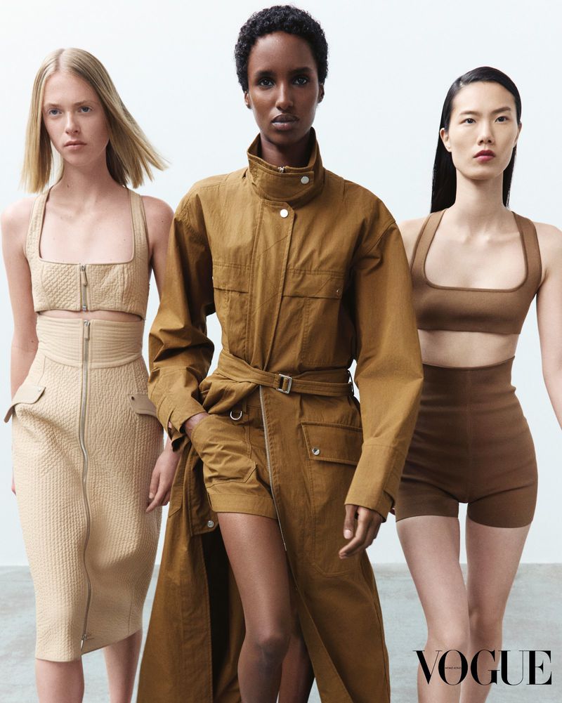 Three female models wearing neutral-toned apparel posing against a plain white studio background for Vogue Hong Kong.