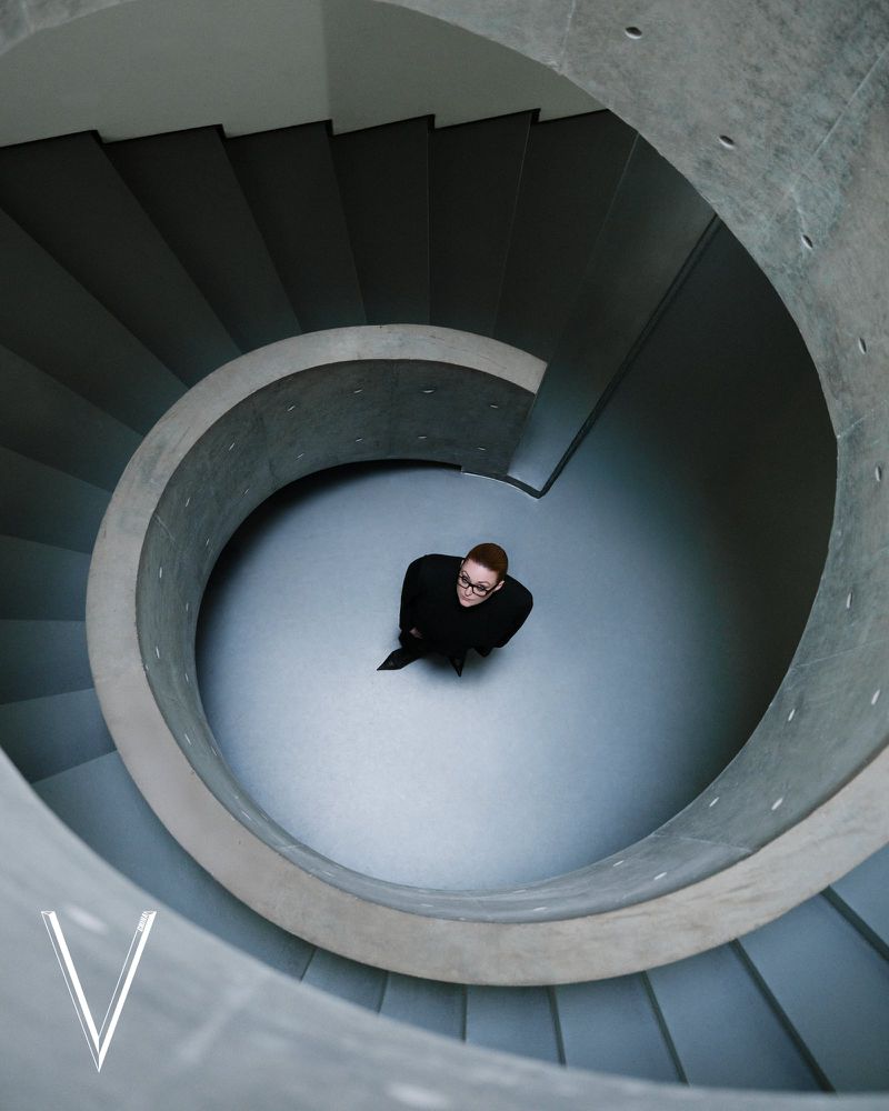 High-angle shot of a person standing inside a sweeping architectural spiral concrete staircase