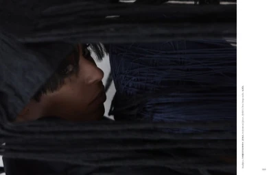 Close-up portrait of a woman framed behind layers of dark yarn or string for Dry Clean Only Magazine