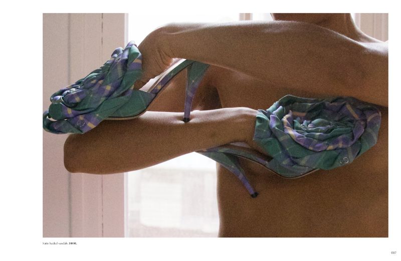 Close-up of a person holding two patterned heeled sandals against their torso for Dry Clean Only Magazine.