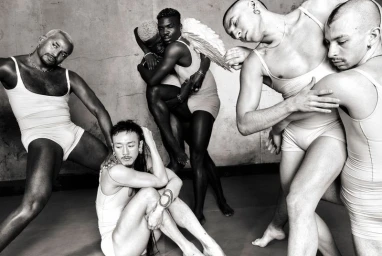 Black and white editorial image featuring FKA twigs and a group of models wearing matching leotards against a textured studio backdrop.