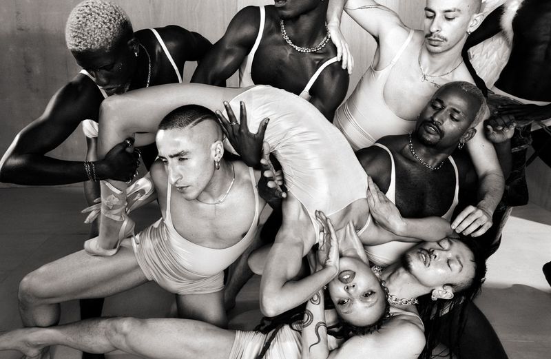 FKA twigs arched horizontally over a group of dancers in matching light tank tops and shorts in 10 Magazine
