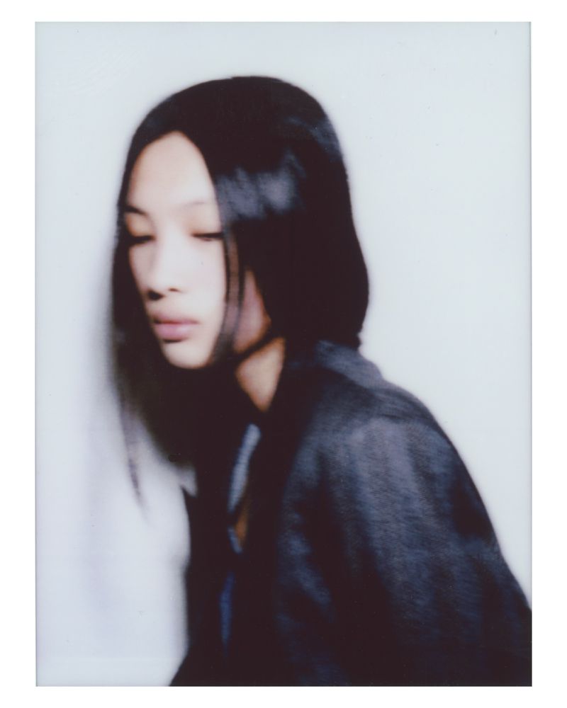 Portrait of a woman with long dark hair wearing a dark jacket against a white seamless background