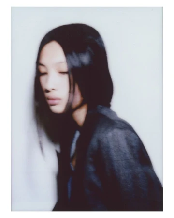 Portrait of a woman with long dark hair wearing a dark jacket against a white seamless background