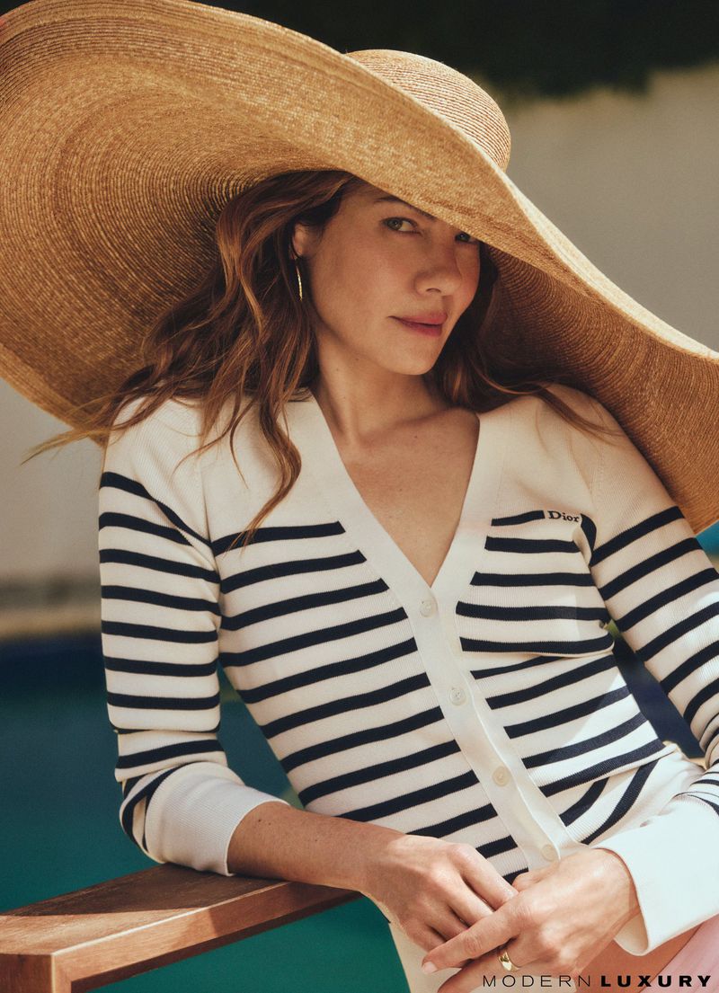 Michelle Monaghan wearing a wide-brimmed straw hat and a striped cardigan for Modern Luxury.
