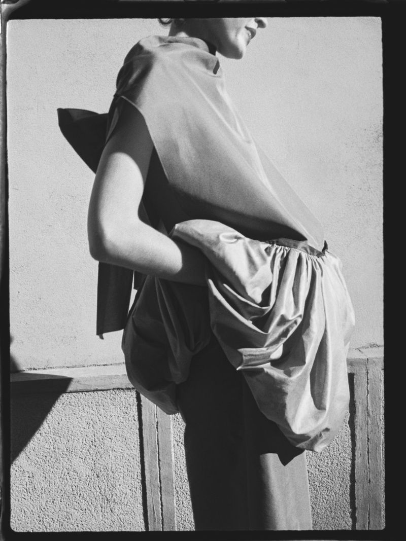 Black and white fashion photo featuring an adult female model in an elegant satin dress with gathered skirt detail and arm detail.