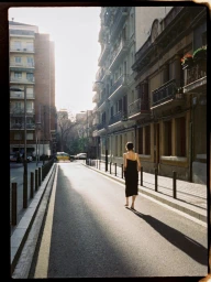 Woman walking barefoot down a sunny city street wearing a black dress for Carven S/S 25