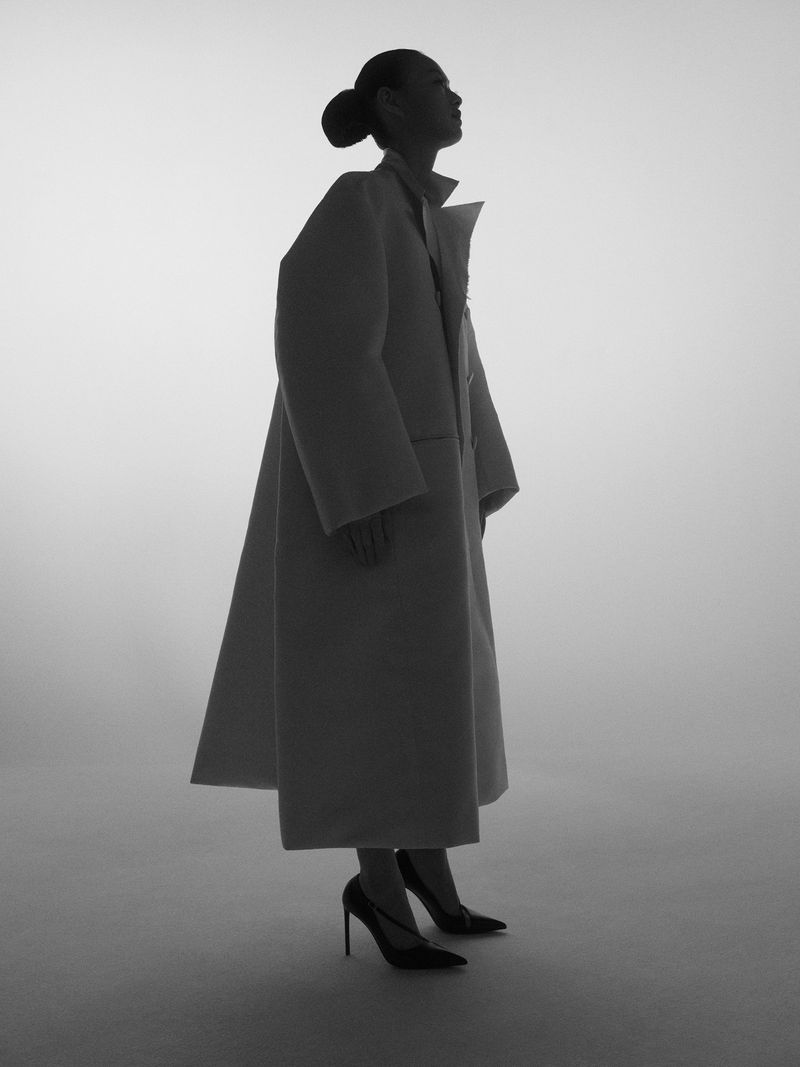 Model in silhouette wearing a long coat and heels against a bright white background for 72 Magazine Shapeshifters project