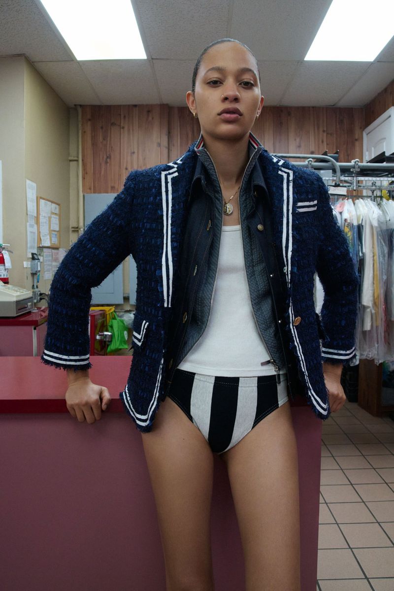 Model Selena Forrest wearing a blue tweed blazer and striped briefs behind a counter in Pop Magazine's Selena South Beach editorial.