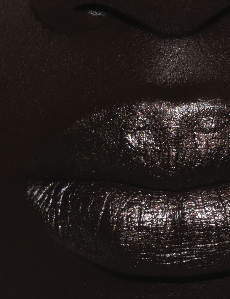 Close-up macro shot of dark lips coated in metallic shimmer makeup with deep moody lighting for Dazed MENA.