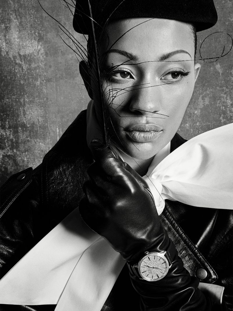 Black and white portrait of model Selena Forrest wearing a leather jacket and gloves with wispy feathers crossing her face.