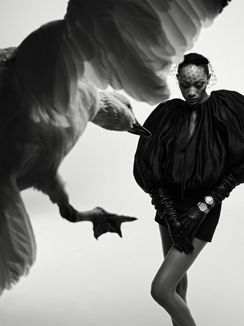 Model Selena Forrest wearing a black outfit with dramatic sleeves and leather gloves alongside a large goose.