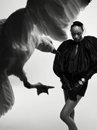 Model Selena Forrest wearing a black outfit with dramatic sleeves and leather gloves alongside a large goose.