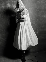 Model Selena Forrest wearing white dress, headscarf and gloves against textured wall in Selena's Dream project for D Repubblica