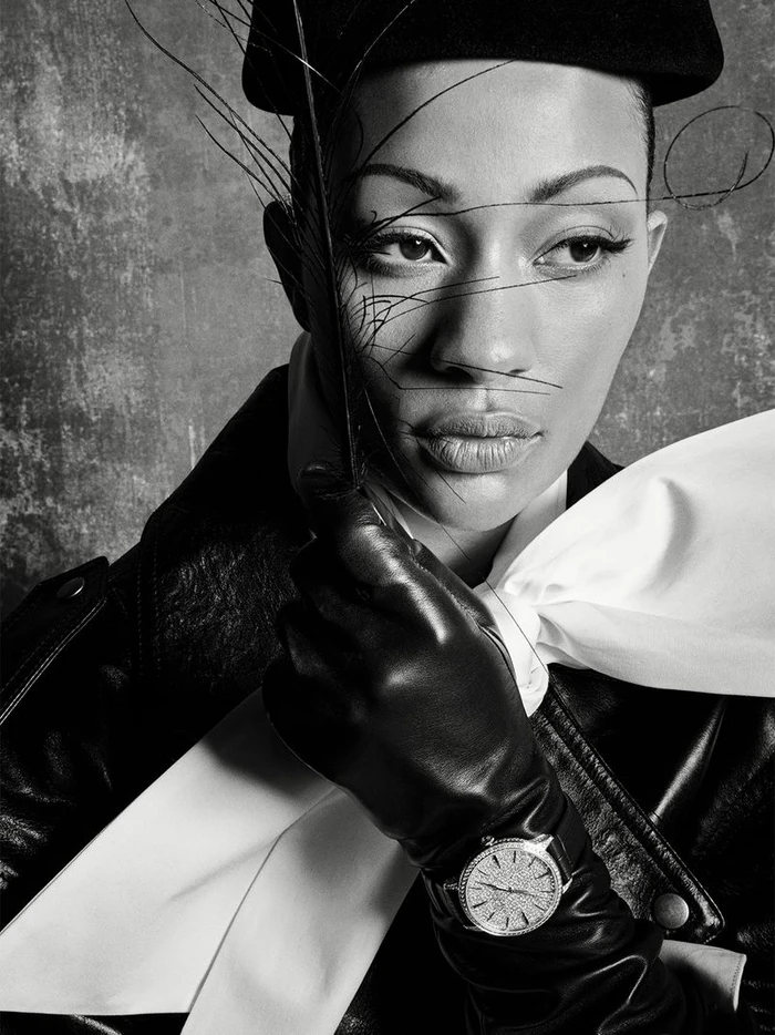Black and white portrait of model Selena Forrest wearing a leather jacket and gloves with wispy feathers crossing her face.